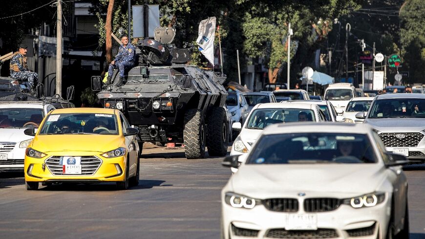 Motorists drive past Iraqi security forces' armoured vehicles in Baghdad on December 26, 2023