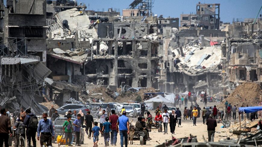 People move past destroyed buildings in Khan Yunis in the southern Gaza Strip 