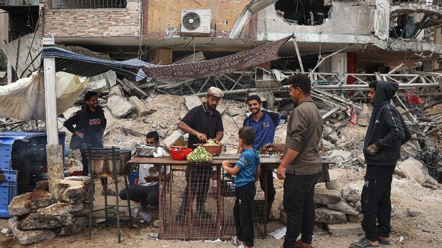 A Palestinian vendor prepares to make falafel sandwiches on a makeshift stall next to the rubble of a destroyed building in Khan Yunis in the southern Gaza Strip