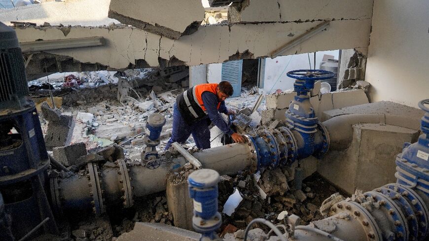 A Palestinian worker checks a pipe at a municipal water management facility that was hit during a strike in Nuseirat, central Gaza