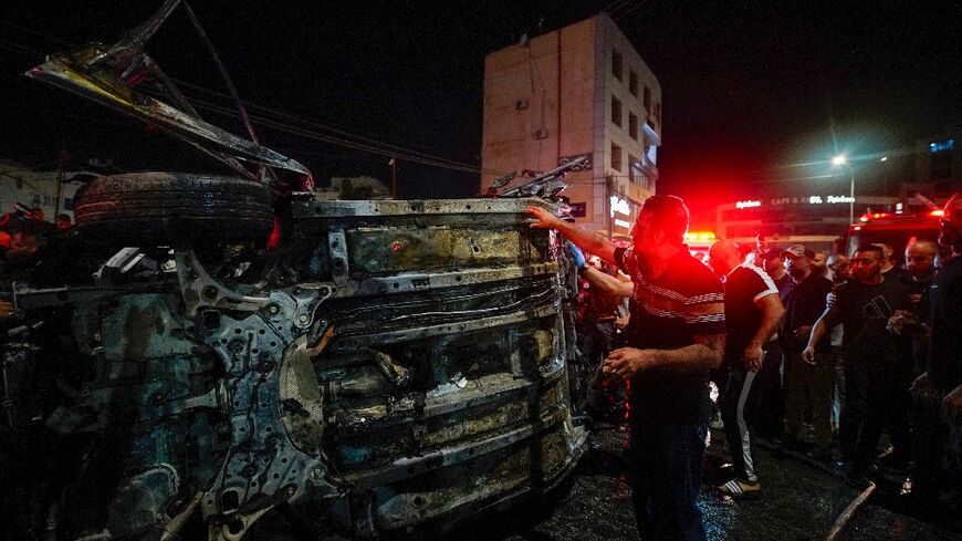 First responders gather around a car hit by an Israeli drone strike in the occupied West Bank city of Jenin