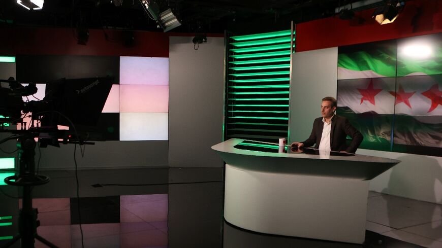 A man delivers a statement in front of the Syrian opposition flag at Syrian state television in Damascus on December 8, 2024, after Islamist-led rebels declared they had taken the Syrian capital