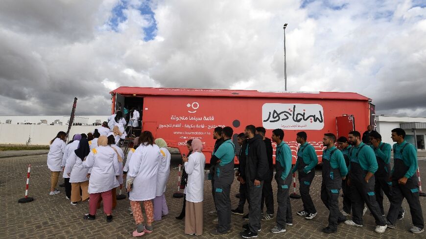 Factory workers line up to watch a film at CinemaTdour's mobile theatre, in Tunisia's town of Djemmal