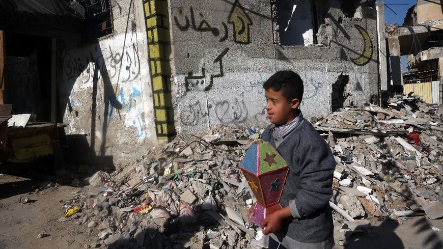A boy carries a Ramadan lantern in a war-devastated neighbourhood of Khan Yunis, southern Gaza, on the eve of the Muslim holy fasting month 