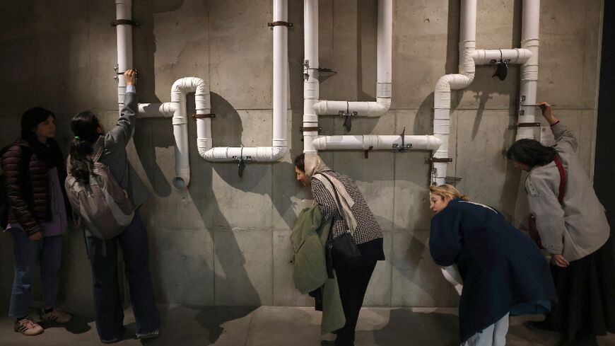 Visitors try out an installation at the SoundScapes exhibition that brings together early sound recordings from Iranian history