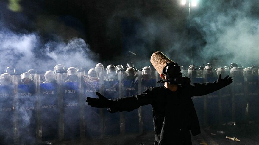 A whirling dervish stands in of front riot police in Istanbul 