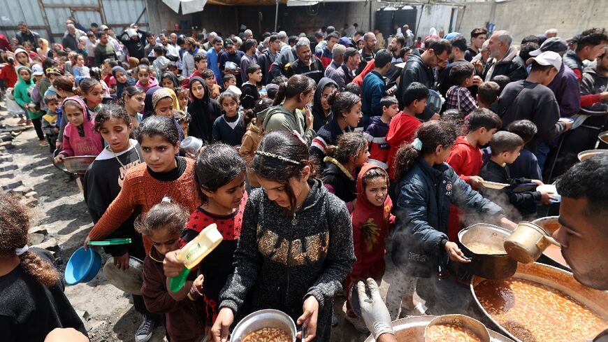 With Gaza under an Israeli aid block, Palestinians wait in front of a free food distribution point to receive a hot meal at Nuseirat refugee camp, central Gaza