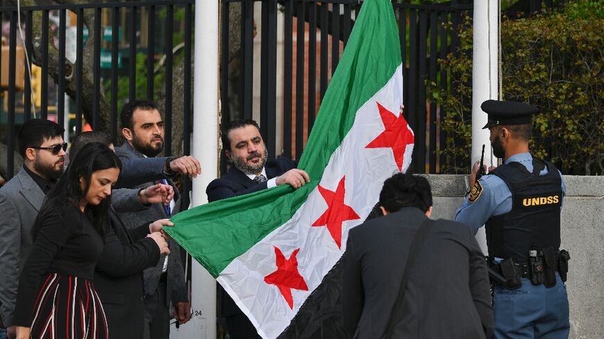Syrian Foreign Minister Asaad al-Shaibani raises the new Syrian flag during a ceremony at United Nations headquarters in New York 