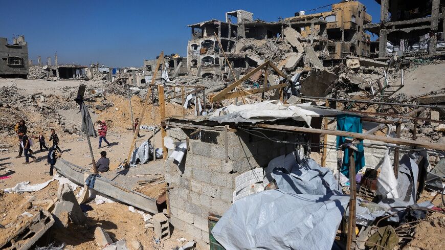 Children gather near a destroyed makeshift shelter following an Israeli strike in Beit Lahia