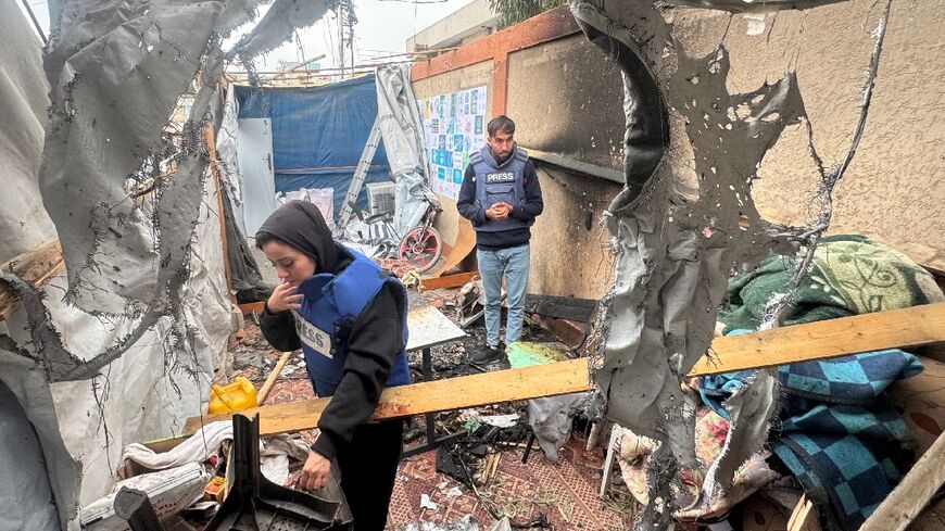 Palestinian journalists inspect the debris and damage after an Israeli strike hit a tent used by journalists in the southern city of Khan Yunis