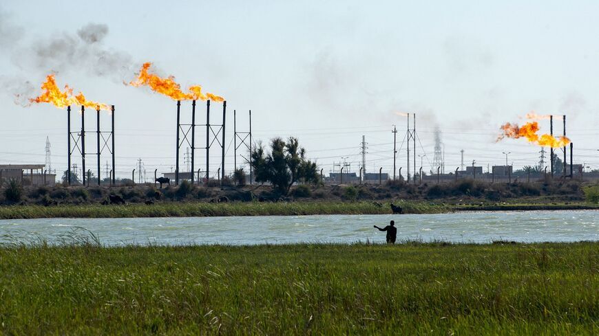 An Iraqi man herds his water buffalos on the Shatt al-Arab river next to the Nahr Bin Omar oil field and facility near Iraq's southern port city of Basra on April 4, 2023. — HUSSEIN FALEH/AFP via Getty Images