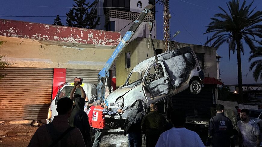 Lebanese soldiers stand guard as a recovery crew removes the vehicle in which a Hamas commander was killed in an Israeli strike.