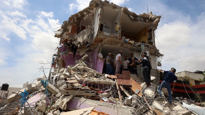 Palestinians inspect the damage at a house following an Israeli raid in the occupied West Bank's village of Tammun