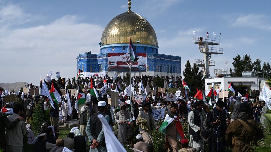 Afghan men holding Taliban flags and Palestinian national flags take part in an anti-Israel protest to show their solidarity with Palestinians after the Friday prayers