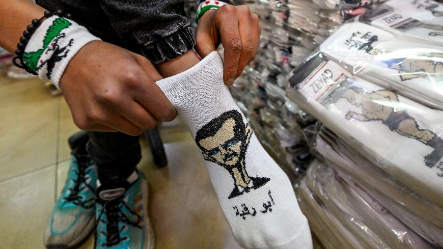 A man tries on a sock bearing a caricature of ousted Syrian leader Bashar al-Assad