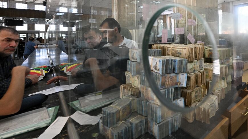 Bank notes of the local currency are piled up as people wait at the central bank in Damascus