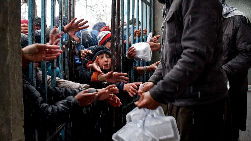 Afghan children receive food aid from a local charity in Mazar-i-Sharif on March 2, 2025