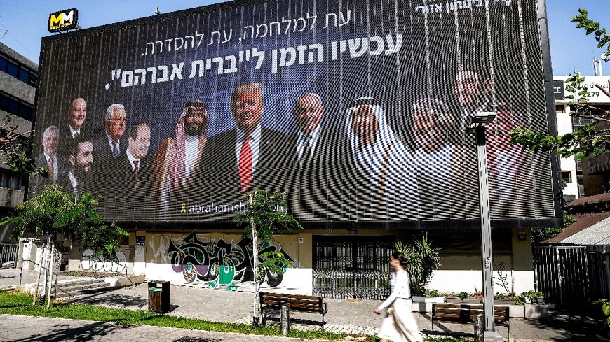A woman walks past a billboard in Tel Aviv that displayed in Tel Aviv thar promotes regional peace with leaders of the region including of Syria