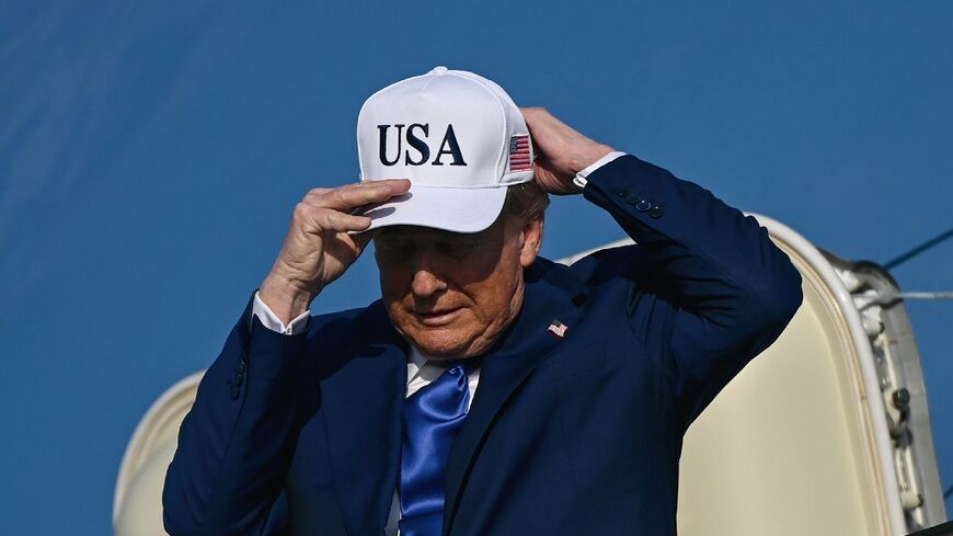 US President Donald Trump adjusts his cap as he exits Air Force One in Amsterdam