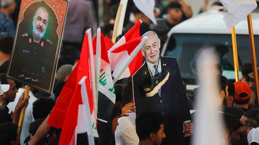 An Iraqi holds a picture of Major General Hossein Salami, head of the Iranian Revolutionary Guard, who was killed in an Israeli airstrike in Tehran, with another holding a cutout of Israeli Prime Minister Benjamin Netanyahu with a shoe around the neck during a protest in Baghdad