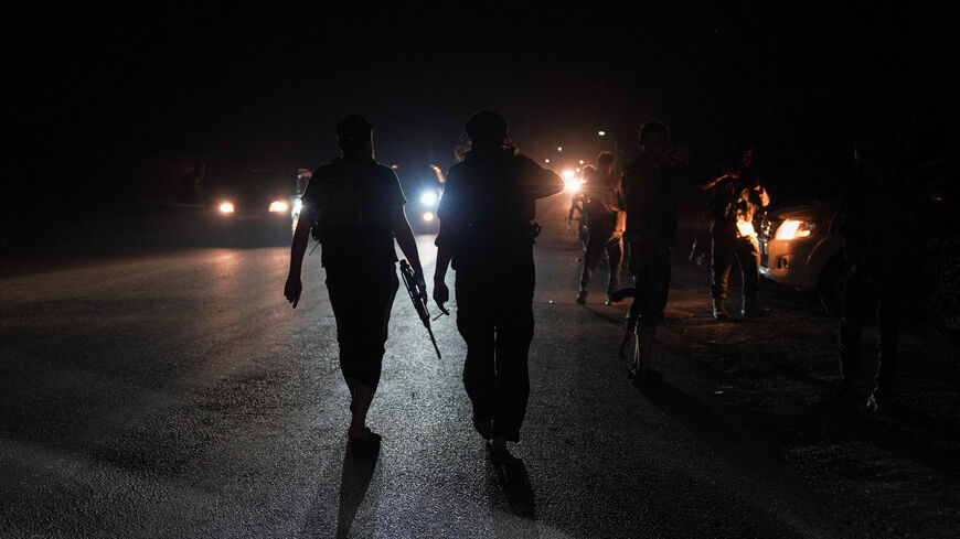 FILE PHOTO: Members of Syrian security forces walk on a road in Sweida countryside, as vehicles transporting other Syrian security forces make their way out of the predominantly Druze city of Sweida, Syria, July 16, 2025. REUTERS/Karam al-Masri/File Photo