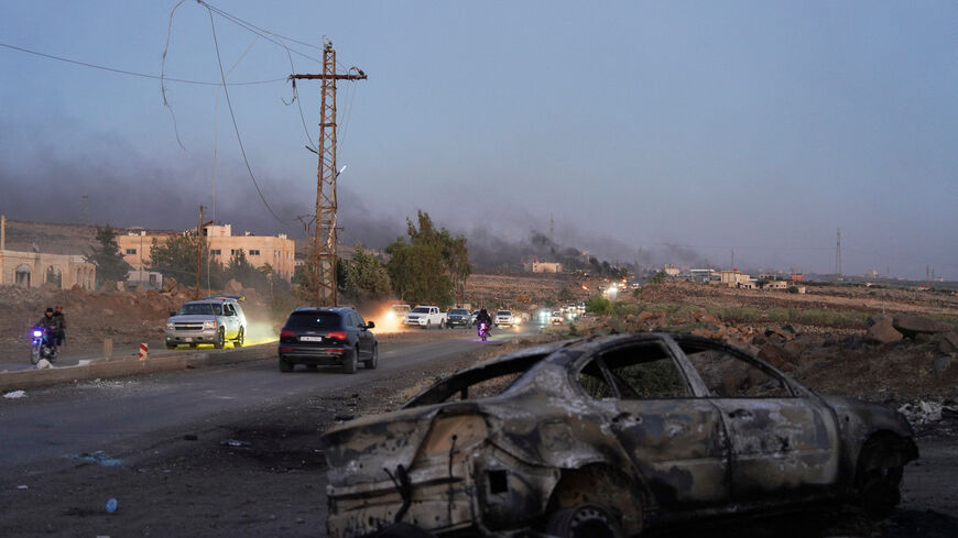 Smoke rises as a damaged car remains along a street, as Sweida province has been engulfed by nearly a week of violence triggered by clashes between Bedouin fighters and factions from the Druze, at Sweida governorate, Syria, July 18, 2025. REUTERS/Karam al-Masri