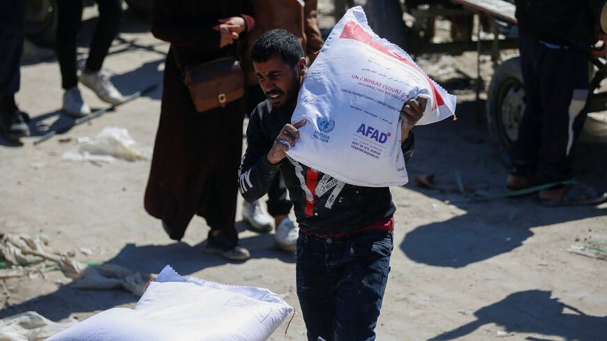 FILE PHOTO: A man carries a sack as Palestinians gather to receive aid provided by UNRWA including food supplies, after Israel says it has ceased entry of humanitarian aid into Gaza, outside a distribution center, at Jabalia refugee camp in northern Gaza Strip, March 2, 2025. REUTERS/Mahmoud Issa/File Photo