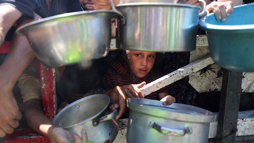 Palestinians wait to receive food from a charity kitchen, amid a hunger crisis, in Gaza City, July 23, 2025. REUTERS/Mahmoud Issa