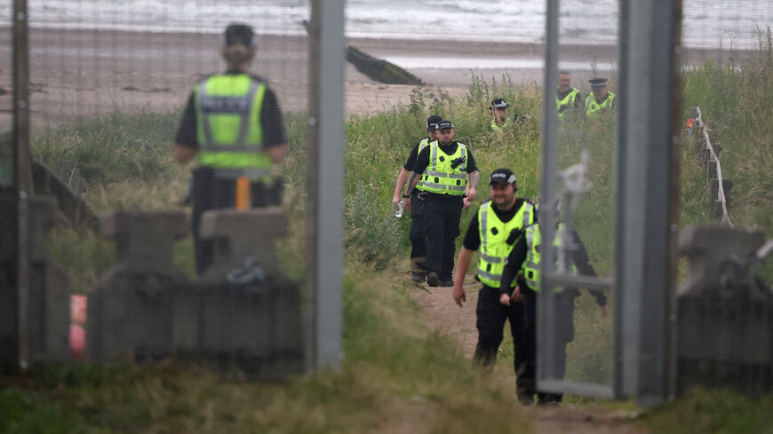 Police officers walk towards a newly erected security fence on the Trump Turnberry golf course ahead of the expected arrival of U.S.President Donald Trump later this week in Turnberry, Scotland, Britain, July 24, 2025. REUTERS/Phil Noble