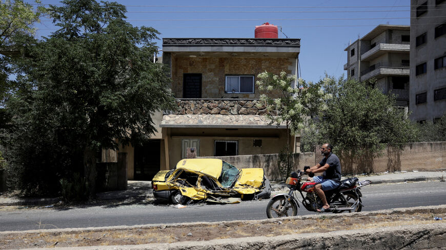 A man rides a motorcycle past a destroyed car, following deadly clashes between Druze fighters, Sunni Bedouin tribes and government forces, in Syria's predominantly Druze city of Sweida, Syria July 25, 2025. REUTERS/Khalil Ashawi/File Photo