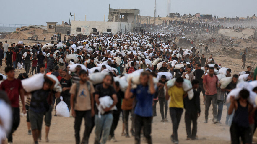 FILE PHOTO: Palestinians carry aid supplies, that entered Gaza on trucks through Israel, in Beit Lahia, in the northern Gaza Strip July 29, 2025. REUTERS/Dawoud Abu Alkas/File Photo
