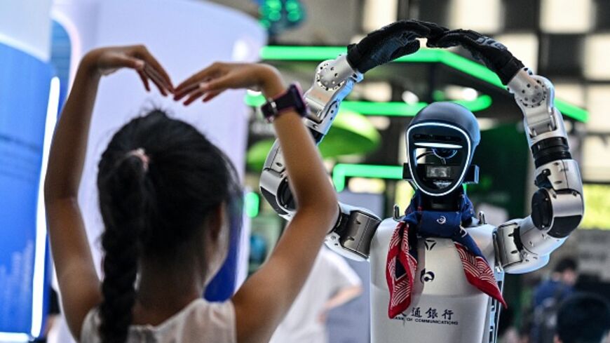 A girl plays with a robot during the World Artificial Intelligence Conference at the Shanghai World Expo and Convention Center on July 28, 2025. (HECTOR RETAMAL/AFP via Getty Images)
