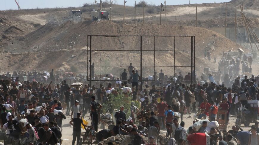 Palestinians wait to receive aid from a distribution point in the Netzarim Corridor, an Israeli military zone that cuts the Gaza Strip in two.