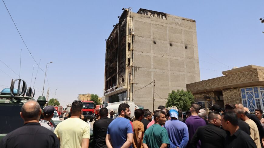 Onlookers gather in front of a shopping mall in the eastern Iraqi city of Kut after a fire tore through it, killing at least 60 people