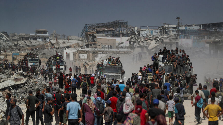 Palestinians climb onto trucks as they seek for aid supplies that entered Gaza through Israel in Beit Lahia, northern Gaza Strip, August 1, 2025. REUTERS/Mahmoud Issa/File Photo