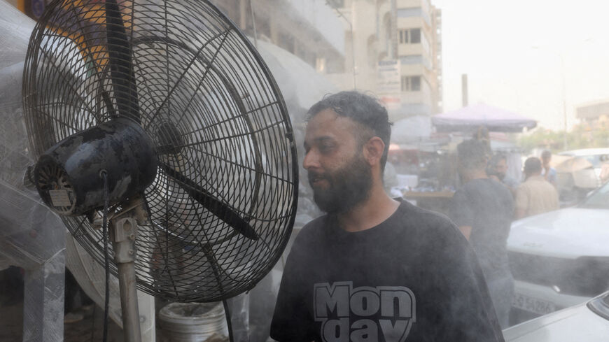 FILE PHOTO: A man cools his face with water mist from sprinklers during a heatwave in Baghdad, Iraq. REUTERS/Ahmed Saad/File Photo