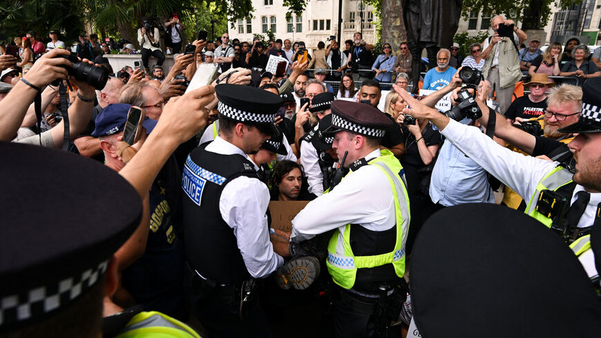 Police officers detain a demonstrator, as people hold placards that read "I oppose genocide, I support Palestine Action" during a rally organised by Defend Our Juries, challenging the British government's proscription of "Palestine Action" under anti-terrorism laws, in Parliament Square, in London, Britain, August 9, 2025. REUTERS/Jaimi Joy