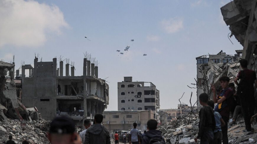 FILE PHOTO: Palestinians look at aid packages that are airdropped over Gaza, in Gaza City, August 8, 2025. REUTERS/Mahmoud Issa/File Photo
