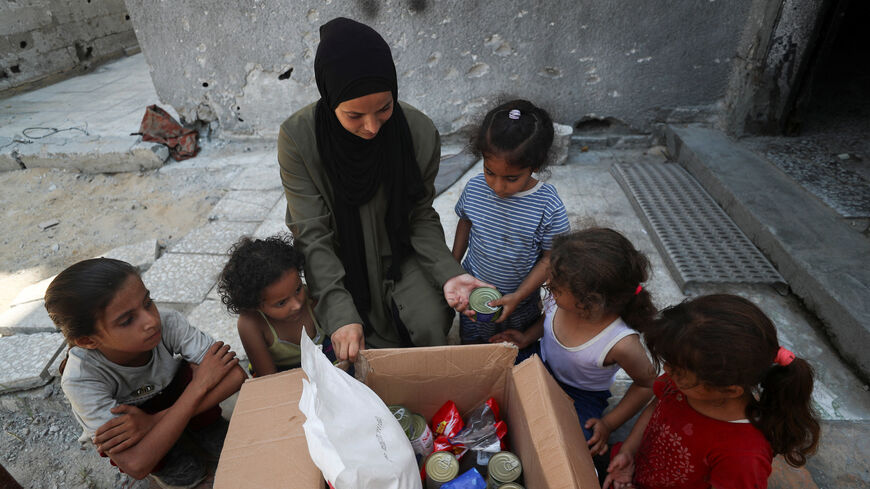 Amal Abu Assi, a Palestinian mother of three, displays the contents of an airdropped food parcel she received, in Gaza City, July 28, 2025. REUTERS/Mahmoud Issa