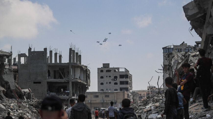 FILE PHOTO: Palestinians look at aid packages that are airdropped over Gaza, in Gaza City, August 8, 2025. REUTERS/Mahmoud Issa/File Photo