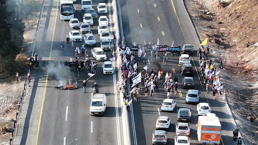 A drone photo shows protesters standing next to burning tires as they block Israel's main highway connecting Jerusalem and Tel Aviv near Latrun, Israel, after families of hostages have called for a nationwide strike to demand the return of all hostages and an end to the war in Gaza, August 17, 2025. REUTERS/Stringer