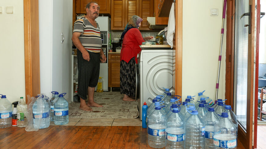 Mehmet and his wife Fatma stand in their kitchen surrounded by large plastic water bottles, as a drought leaves some homes without running water for weeks, in Marmara Ereglisi, in the northwestern Tekirdag province, Turkey, August 11, 2025. REUTERS/Dilara Senkaya