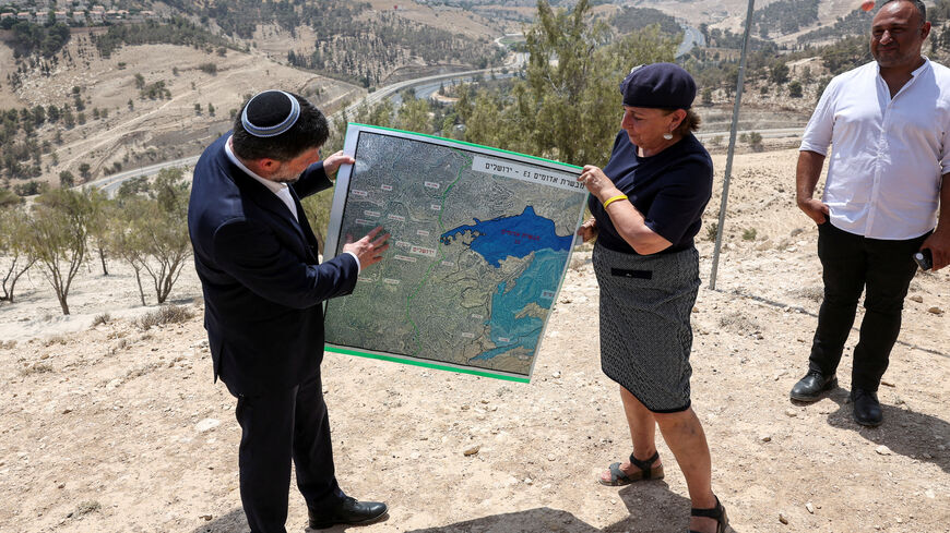 FILE PHOTO: Israeli Finance Minister Bezalel Smotrich and a woman hold a map that shows the long-frozen E1 settlement scheme, that would split East Jerusalem from the occupied West Bank, on the day of a press conference near the Israeli settlement of Maale Adumim, in the Israeli-occupied West Bank, August 14, 2025. REUTERS/Ronen Zvulun/File Photo