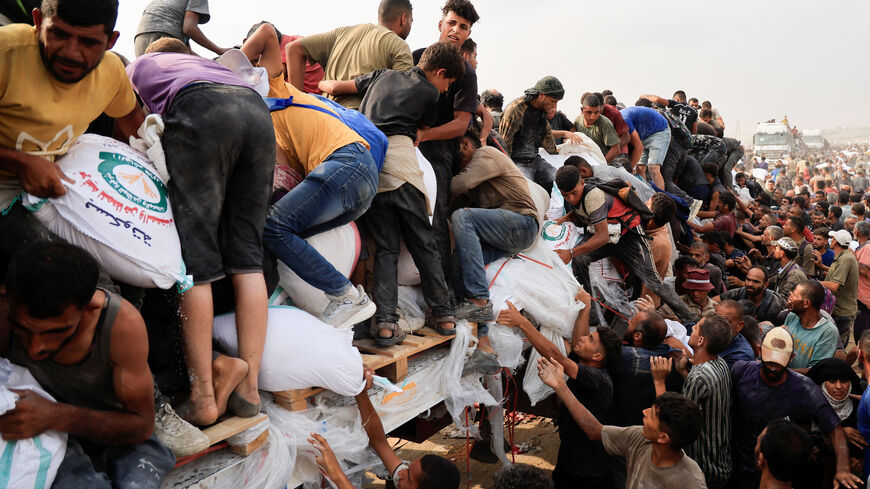 FILE PHOTO: Palestinians scramble to collect aid supplies from trucks that entered through Israel, in Khan Younis, southern Gaza Strip, August 12, 2025. REUTERS/Hatem Khaled/File Photo