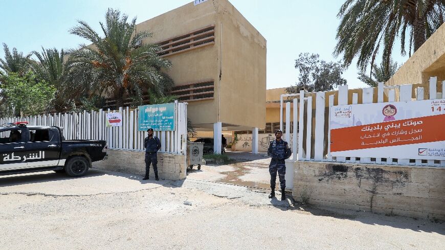 Libyan security officers stand guard outside a school in the capital Tripoli being used as a polling station in Saturday's municipal election.