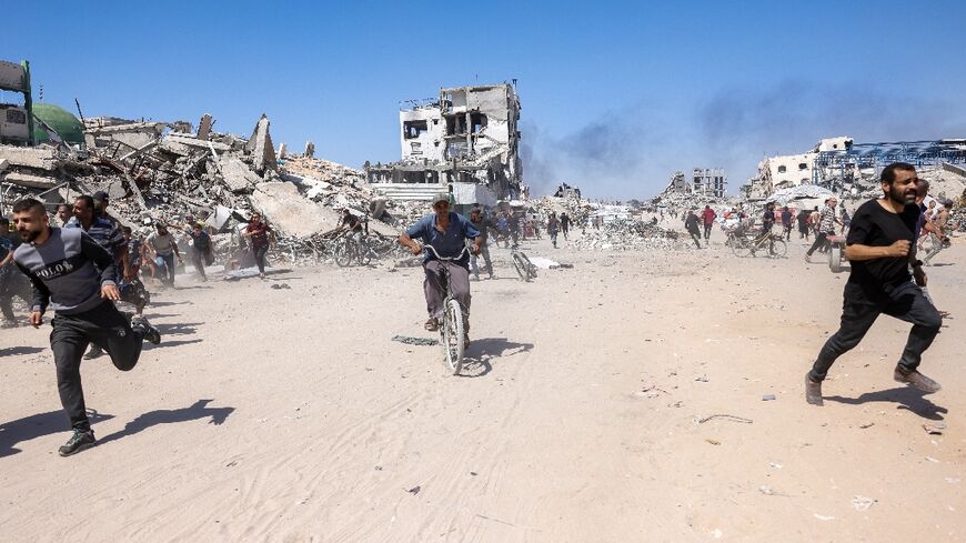Palestinians run for cover during an Israeli drone strike in northern Gaza on May 23, 2025