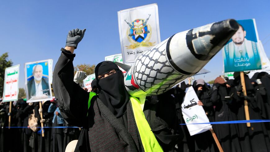 A Yemeni woman holds up a mock missile decorated with the colors of the Palestinian flag and the checkered keffiyeh during a protest in Sanaa to denounce strikes on Yemen and Israel's bombardment of Gaza, on Jan. 15, 2025.