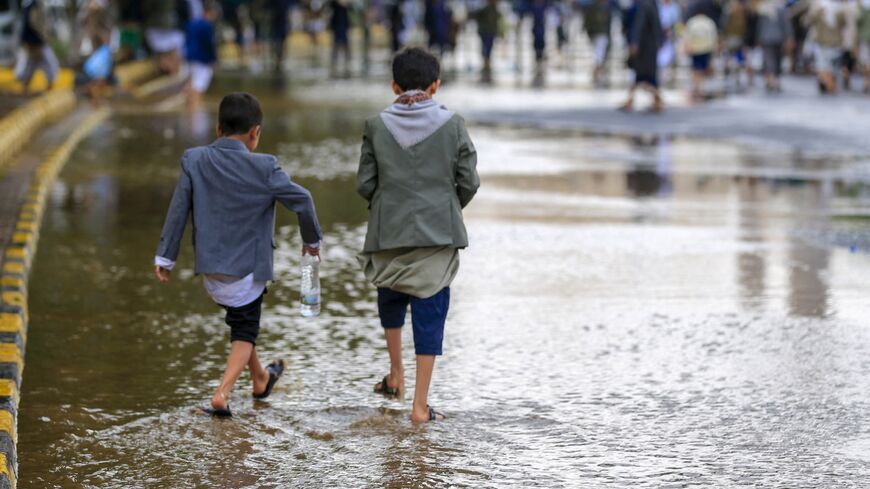 Yemeni boys walk on a flooded road during a rally in solidarity with Palestinians in the Houthi-run capital Sanaa on Aug. 1, 2025.