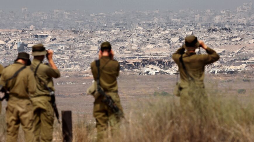 Israeli army soldiers look at the destruction in Gaza from the border with the Palestinian territory, Aug. 13, 2025.