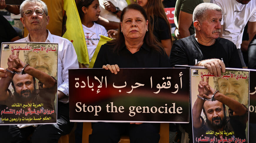 Fadwa, wife of leading member of the Palestinian Fatah party Marwan Barghouti, the most high-profile Palestinian detainee in Israeli custody, lifts a placard during a rally to support him in Ramallah city in the occupied West Bank, attended by politician Mustapha Barghouti (L) and political activist Omar Assaf on August 19, 2025. The UN's human rights office on Ausust 19 condemned Israel's far-right national security minister Itamar Ben Gvir for taunting Barghouti, who has spent more than 20 years behind ba